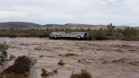 A tour bus is seen on its side after it was swept away and flipped over near Kingman, Ariz., on Sunday, July 28, 2013. All 33 people on board were OK.