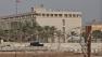 A Bahraini armored personnel vehicle and personnel reinforce U.S. Embassy security just outside of a gate to the building, surrounded in barbed wire, in Manama, Bahrain, on Sunday, Aug. 4, 2013.
