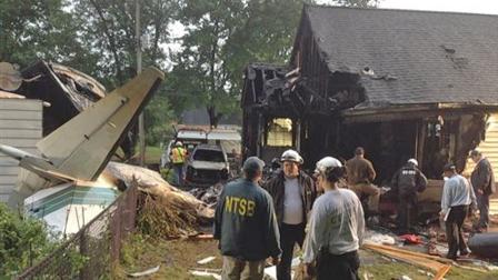 In this photo provided by the National Transportation Safety Board, NTSB senior air safety investigator Bob Gretz confers with emergency crews Friday Aug. 9, 2013 following the crash of a Rockwell 960B airplane into a neighbohood in East Haven, Conn.