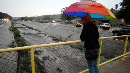 Kelsey McKiel watches as Camp Creek, normally a small stream, races with soot and mud down 31st Street after a flash flood from the Waldo Canyon Fire.
