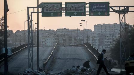 In this Saturday, Oct. 27, 2012 photo, a Syrian resident walks at sunset through a crossroad in downtown as mortar explosions, not seen, sound in the distance, in the Saif al-Dawleh, neighborhood, Aleppo, Syria.