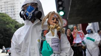 A protester wearing a protective suit and mask holds up a bottle of Monsantos Roundup herbicide during a protest against Monsanto in Sao Paulo, Brazil, Saturday, May 25, 2013.