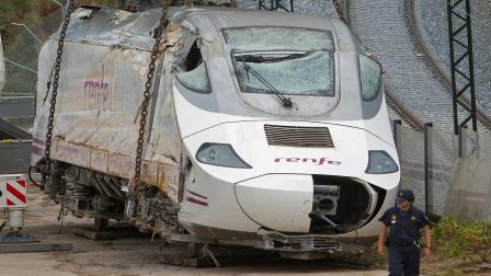 Police stand guard as a wreckage of a crashed train is seen ready to be deposited in Santiago de Compostela, Spain, Sunday July 28, 2013.