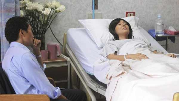 Jin-Soo Kwon (Daniel Dae Kim) sits and watches his wife Sun-Hwa Kwon (Yunjin Kim) as she sleeps on a hospital bed.