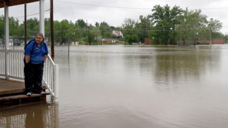 Erica Cross stands on a friends porch surrounded by floodwater Tuesday, April 26, 2011, in Poplar Bluff, Mo.