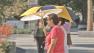 People walk with umbrellas to shield their faces from the sweltering sun in downtown Los Angeles on Friday, Sept. 3, 2013.