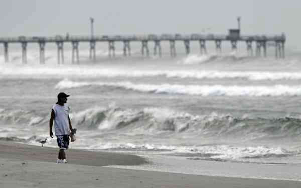 Almon Telling looks at the surf as he walks...