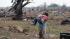 A woman carries her child through a field near the collapsed Plaza Towers Elementary School in Moore, Okla., May 20, 2013.