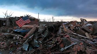 An American flag blows in the wind at sunrise atop the rubble of a destroyed home a day after a tornado moved through Moore, Okla., Tuesday, May 21, 2013.