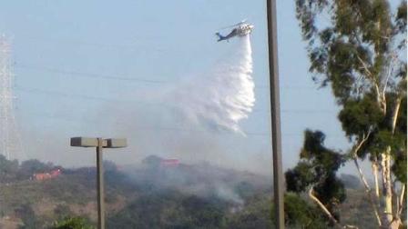 A helicopter is seen dousing a fire off the 210 Freeway in Glendora Saturday, June 2, 2012.