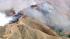 Smoke rises above the hills of Castaic, where a...