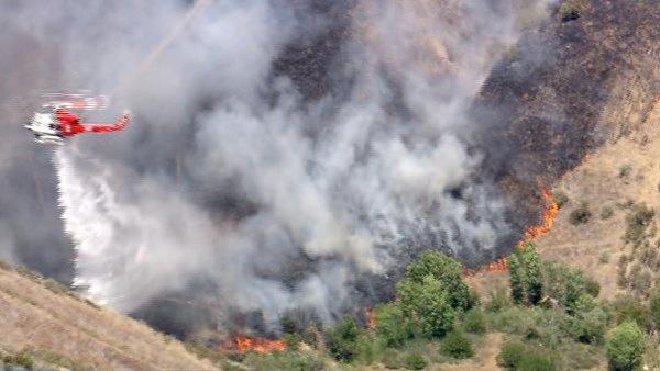 A helicopter makes a water drop on a brush fire burning in the Castaic hills on Friday, June 8, 2012. Fanned by winds, the blaze grew from 3 acres to more than 50 in less than three hours.
