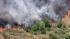 Smoke rises above the hills of Castaic, where a...