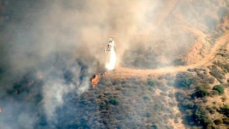 A helicopter is seen dousing part of a major brush fire in Beaumont on Saturday, June 16, 2012.