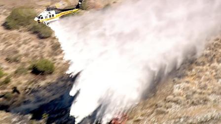 A helicopter makes a water drop over a fire burning in at the Los Angeles County and San Bernardino County border on Saturday, June 30, 2012.