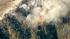 Smoke rises above a wildfire burning in the San...