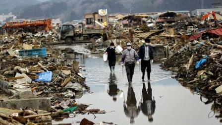 A Japanese family walks along the flooded street at an area devastated by the March 11 earthquake and tsunami in the port town of Kesennuma
