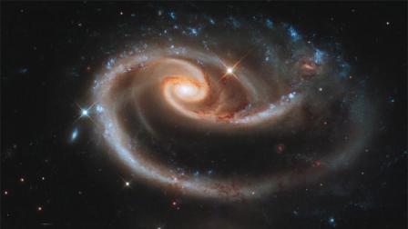 The larger of the spiral galaxies, known as UGC 1810, has a disk that is distorted into a rose-like shape by the gravitational tidal pull of the companion galaxy below it, known as UGC 1813.