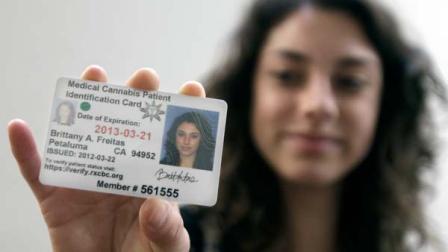 Britt Freitas holds up her new medical cannabis patient identification card at the Patient ID Center