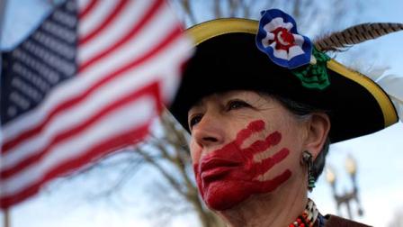 Susan Clark of Santa Monica, Calif., who opposes health care reform, stands with a red hand painted over her mouth to represent what she said is socialism taking away her choices and rights, in front of the Supreme Court