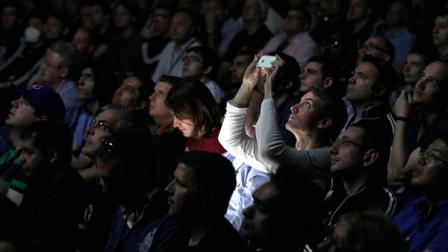 Attendees watch a video presentation on new products during the Apple Developers Conference in San Francisco, Monday, June 11, 2012.