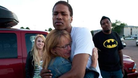 Judy Goos, second from left, hugs her daughters friend, Isaiah Bow, 20, while eye witnesses Emma Goos, 19, left, and Terrell Wallin, 20, right, gather outside Gateway High School where witness were brought for questioning Friday, July 20, 2012 in Denver.