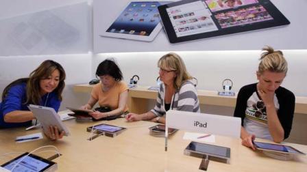 In this Thursday, July 19, 2012, photo, an Apple worker, left, gives a tutorial on Apple iPad to customers at an Apple store in Palo Alto, Calif. Apple Inc. reports quarterly financial results after the market closes on Tuesday, July 24.