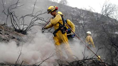 Firefighter James Heaton, front, hoses down hotspots in the Angeles National Forest Wednesday Sept. 5, 2012 near Los Angeles. Fire crews are getting help from rain in battling a 3,800-acre fire in the San Gabriel Mountains northeast of Los Angeles.