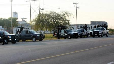 A group of Mexican federal police stand in front of the prison in Piedras Negras, Mexico