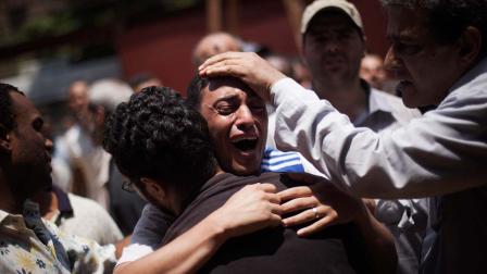 An Egyptian man cries outside a morgue after carrying the corpse of his brother killed near the Republican Guard building in Cairo