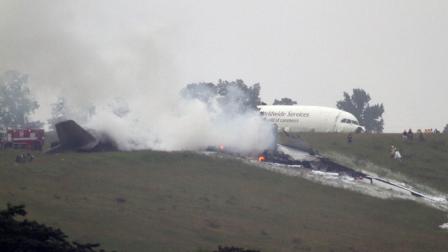 Debris burns as a UPS cargo plane lies on a hill at Birmingham-Shuttlesworth International Airport after crashing on approach, Wednesday, Aug. 14, 2013, in Birmingham, Ala.
