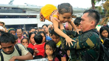 Philippine military personnel try to prioritize children and women first as people wait for evacuation flights in Tacloban, central Philippines