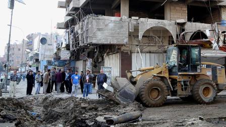 Civilians clear the aftermath of a car bomb attack in the crowded commercial area of Karrada, Baghdad, Iraq
