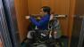 Man in wheelchair in small elevator at Independent Living Resources Center on Mission Street