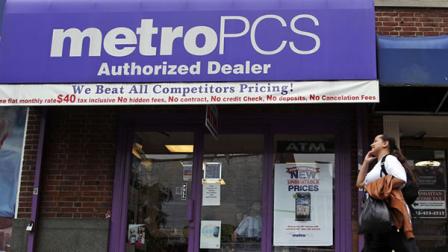 A pedestrian talks on a cellular phone as he walks past a MetroPCS authorized dealer, Wednesday, Oct. 3, 2012 in New York.