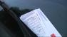 A parking ticket under a cars windshield wiper