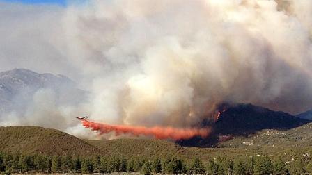 In this photo made Wednesday, July 17, 2013, and released by the U.S. Forest Service, a DC-10 drops fire retardant along an edge of the Mountain Fire near Lake Hemet, California