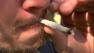 A man smokes a marijuana joint.