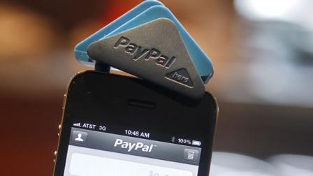 A PayPal employee holds an iPhone with a PayPal Here card reader attached, in San Francisco, Calif., March 15, 2012.