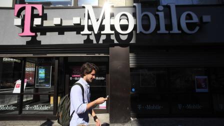 A man using a cellphone passes a T-Mobile store, Wednesday, Sept. 12, 2012 in New York. (AP Photo/Mark Lennihan)