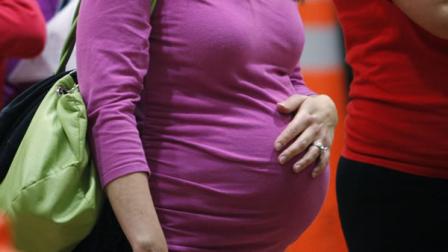 A pregnant woman stands in line.