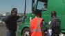 Security talks to a truck driver in a lot near the Port of Oakland