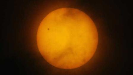 A tiny dot of the planet Venus is seen on the northwest side of the Suns disc