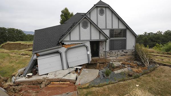 This photo taken Monday, May 6, 2013 shows the wreckage of the Tudor-style dream home of Robin and Scott Spivey who were forced to abandon after the ground gave way causing it to drop 10 feet below the street in Lakeport, Calif.