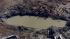 Workers and officials look over a crater caused...