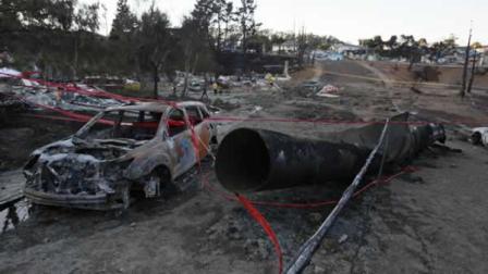 A ruptured gas pipe that caused a massive explosion is shown beside a burned car in San Bruno, Calif.