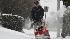 Bob Poole clears snow from a sidewalk in...
