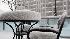 Snow piles up on the outdoor table and chairs in...