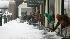 Workers shovel snow along a walkway at the open...