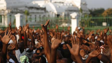 People raise their hands during a national day of mourning in front of the national palace in Port-au-Prince, Haiti.